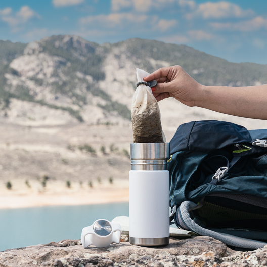 Toddy Go Brewer in stainless and white draining coffee in lid on a hike